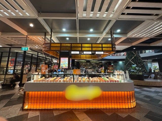 Doughnut and coffee counter with bright orange lighting in a shopping centre.