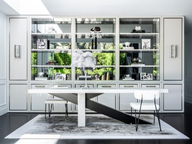 Modern dining room with a sculptural white table, minimalist chairs, and built-in shelving decorated with art and books.